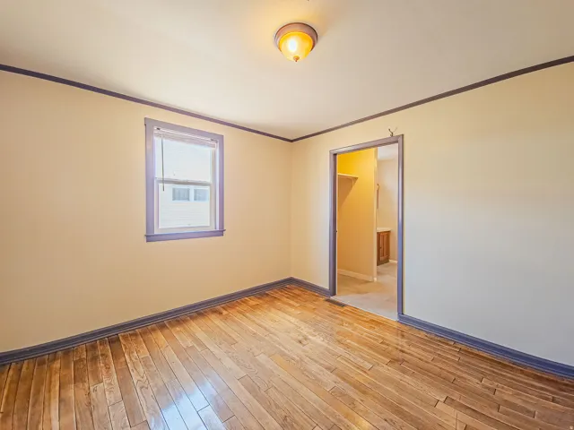 Room featuring wood-finish flooring, a window with blinds, and a neutral wall color