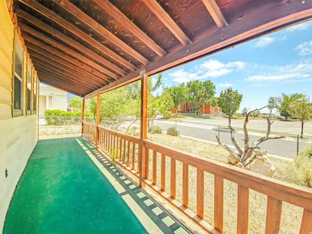 Covered porch featuring a wood-finish ceiling, wood railing, and green floor surface