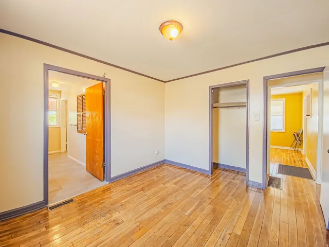 Room featuring wood-finish flooring, light-toned walls, and dark trim