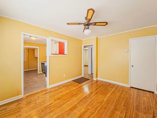 Room featuring wood-finish flooring, a ceiling fan with light fixture, and warm yellow wall paint