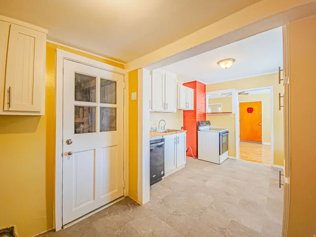 Kitchen with white cabinetry, a built-in dishwasher, and a freestanding range