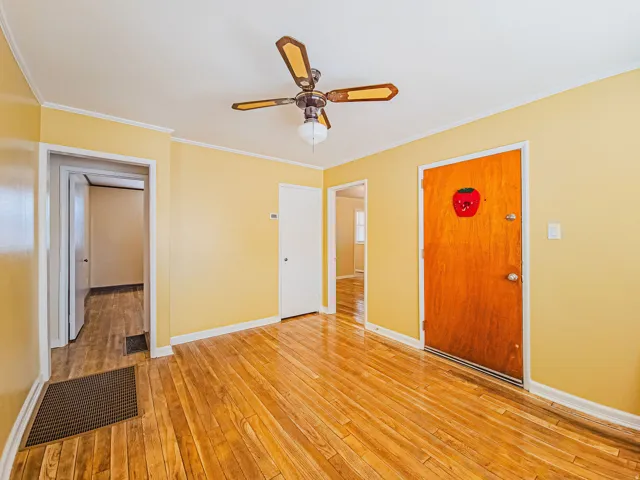 Hardwood flooring extends throughout this room with a ceiling fan light fixture, white trim, and yellow painted walls
