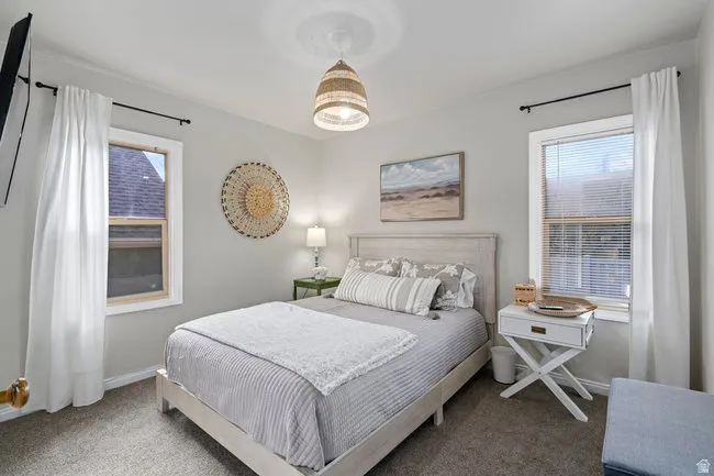 Carpeted room featuring light gray walls and two windows with blinds and curtains