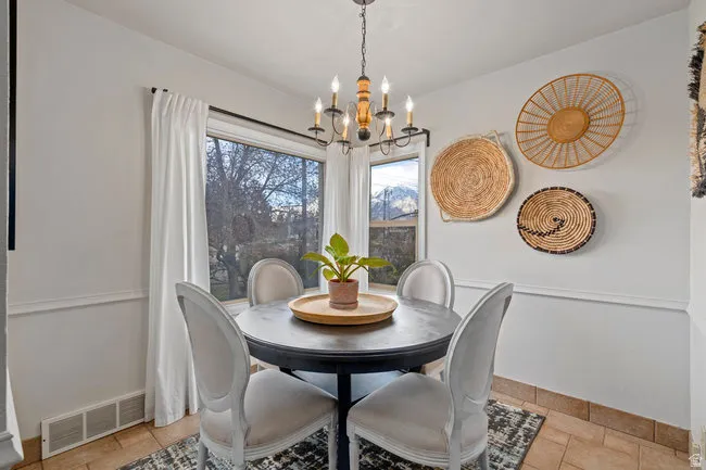 Corner dining area with a multi-pane window, tile flooring, and white wall paneling
