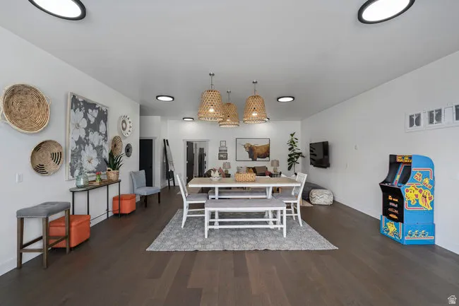 Open-concept living area featuring dark wood-finish flooring, recessed ceiling lighting, and a dining space with three woven pendant fixtures