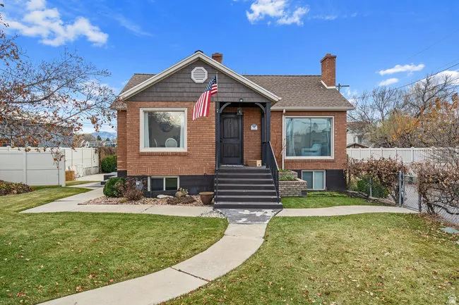 Brick-clad exterior featuring a prominent front porch, shingled gable, and curved bay window