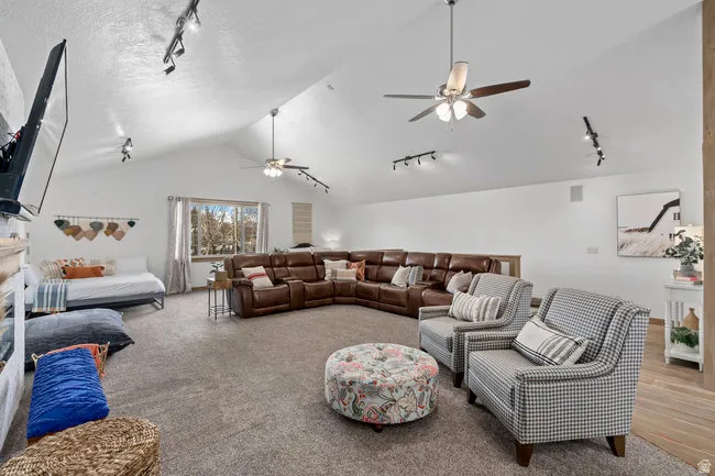 Spacious room featuring vaulted ceilings, recessed lighting, track lighting, and multiple ceiling fans