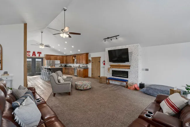 Spacious open-concept living area featuring a vaulted ceiling with recessed lighting and ceiling fans