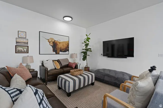 Spacious living area featuring neutral wall tones, a ceiling-mounted light fixture, and textured carpet flooring