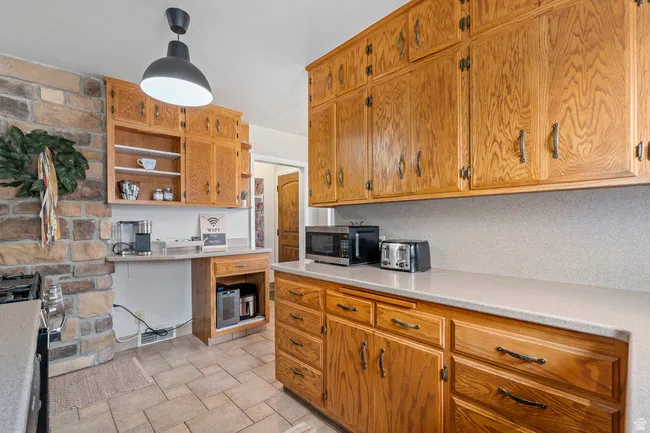 Kitchen featuring extensive wood cabinetry with dark hardware, light-toned countertops, and a stone-faced accent wall