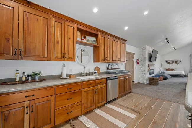 Kitchenette featuring wood cabinetry, light-toned countertops, and a stainless steel dishwasher