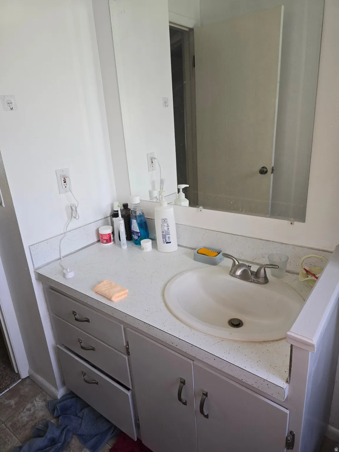 Bathroom vanity featuring a white countertop with integrated sink, dual-handle faucet, and white cabinetry with drawer and cabinet storage