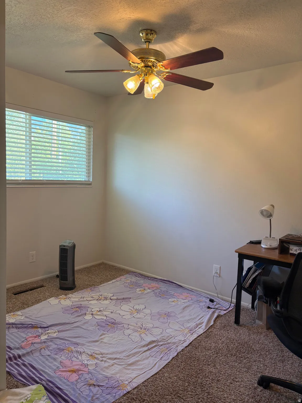 Ceiling fan with light fixture, textured ceiling, window with horizontal blinds, neutral wall tones, and carpet flooring