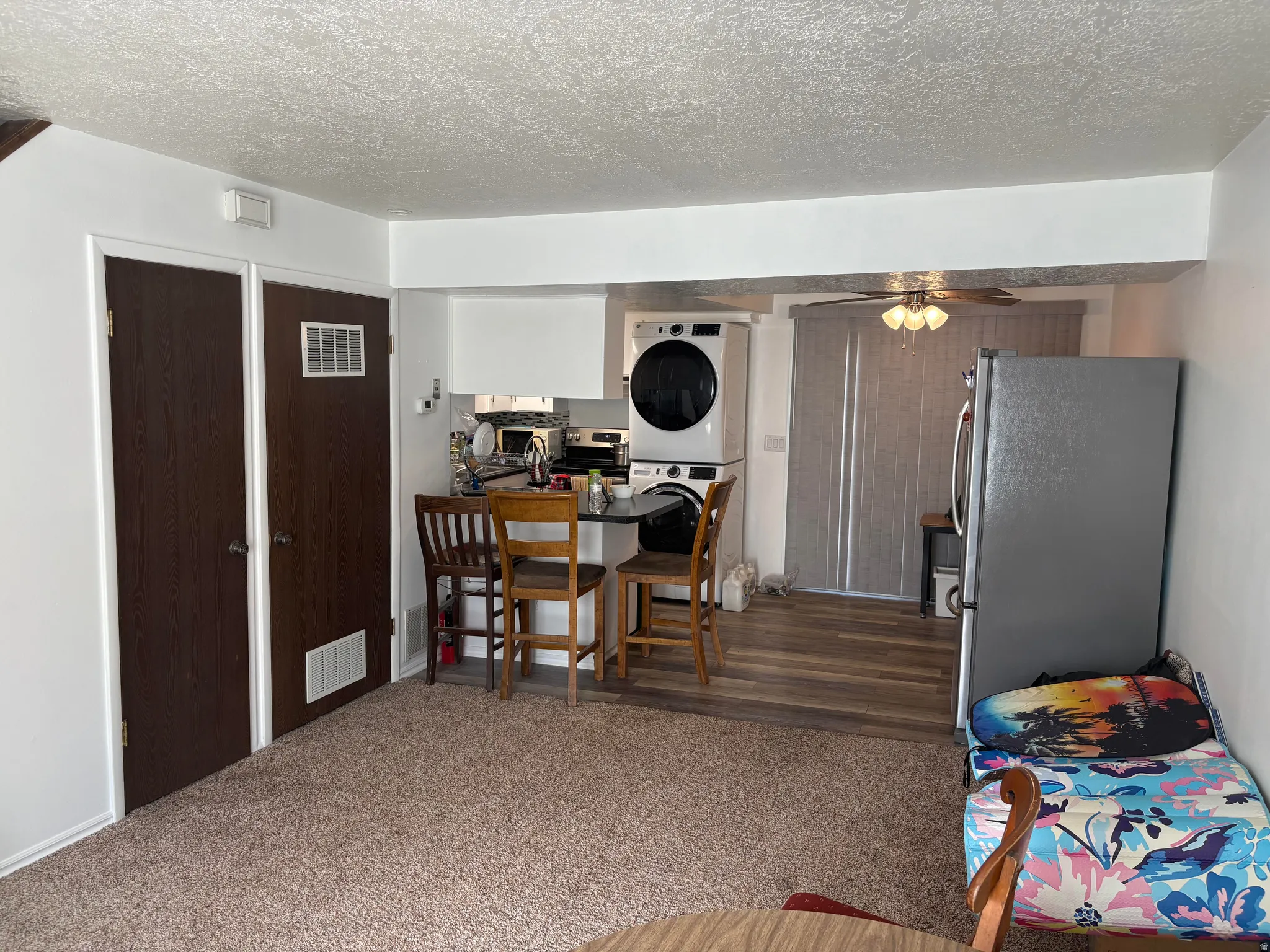 Open-concept living space with carpeted flooring transitioning to wood-finish flooring