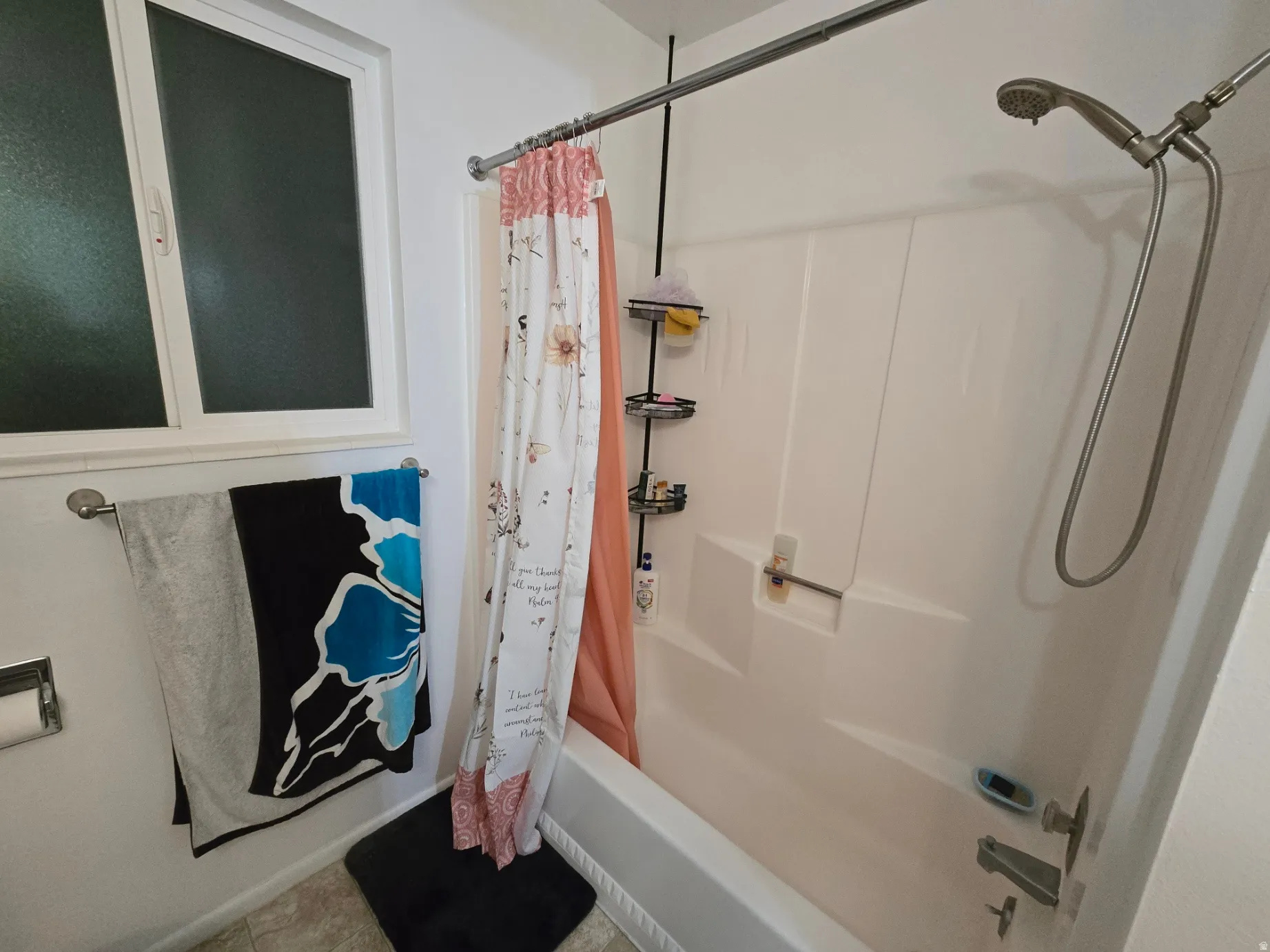 White bathtub and shower combination with a handheld shower fixture