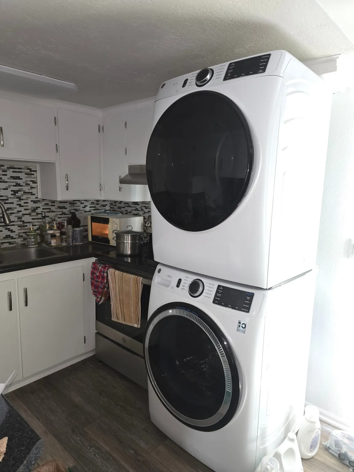 Compact laundry area featuring a stacked washer and dryer unit