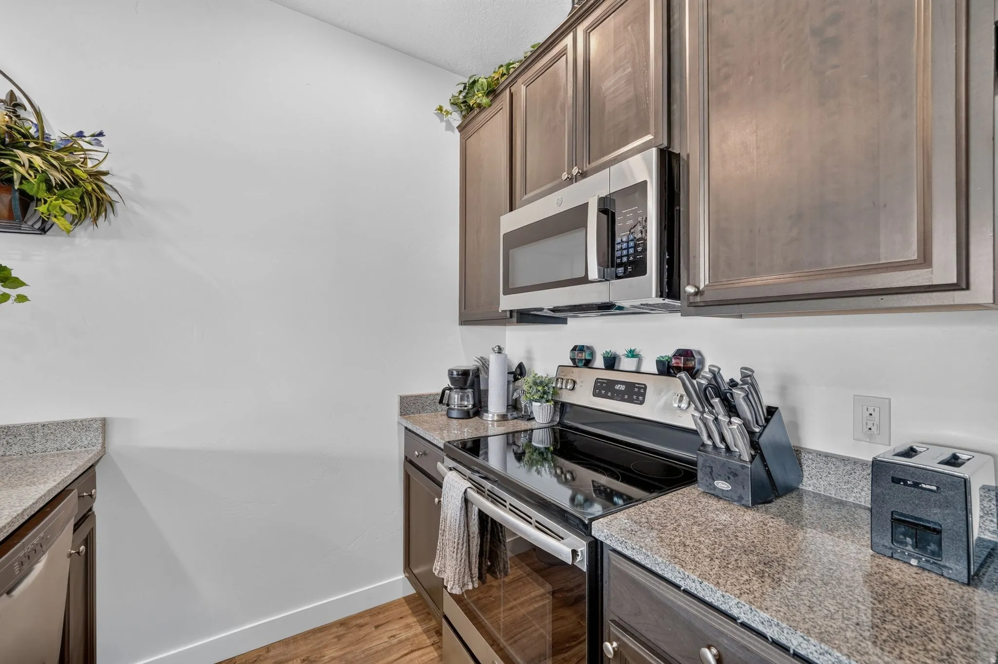 Kitchen area featuring wood-finish flooring, dark wood cabinetry, and speckled countertops