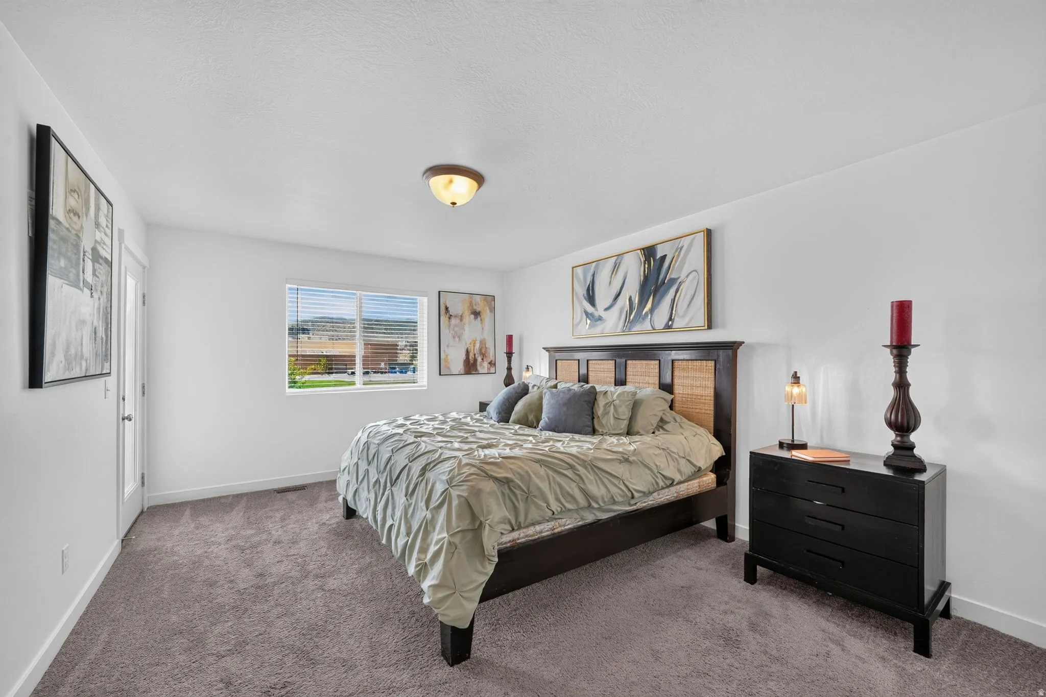 Carpeted room featuring a window with horizontal blinds, a ceiling-mounted light fixture, and white painted walls