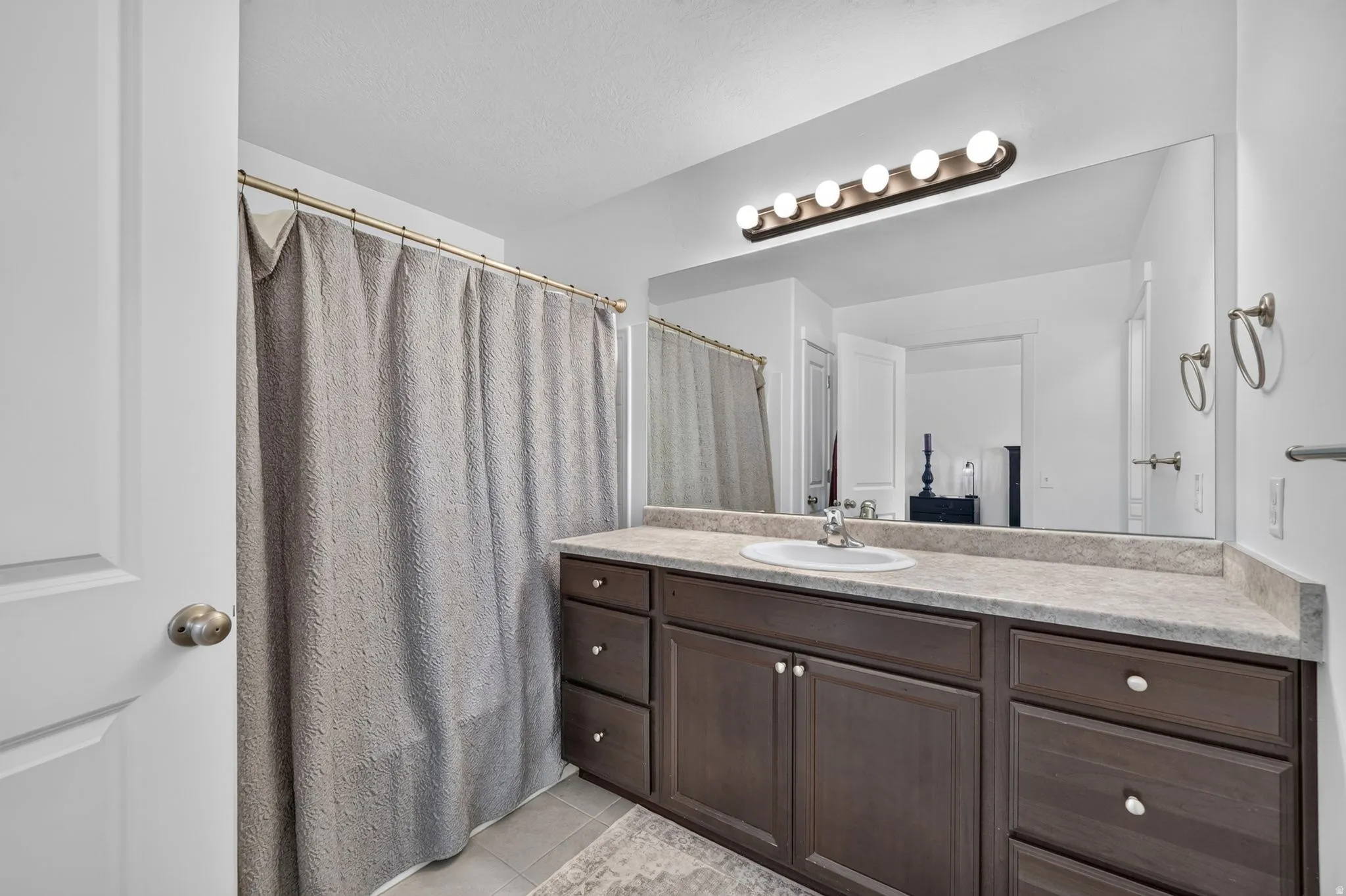 Bathroom featuring a dark wood-finish vanity with ample storage, an integrated sink, and a large mirror