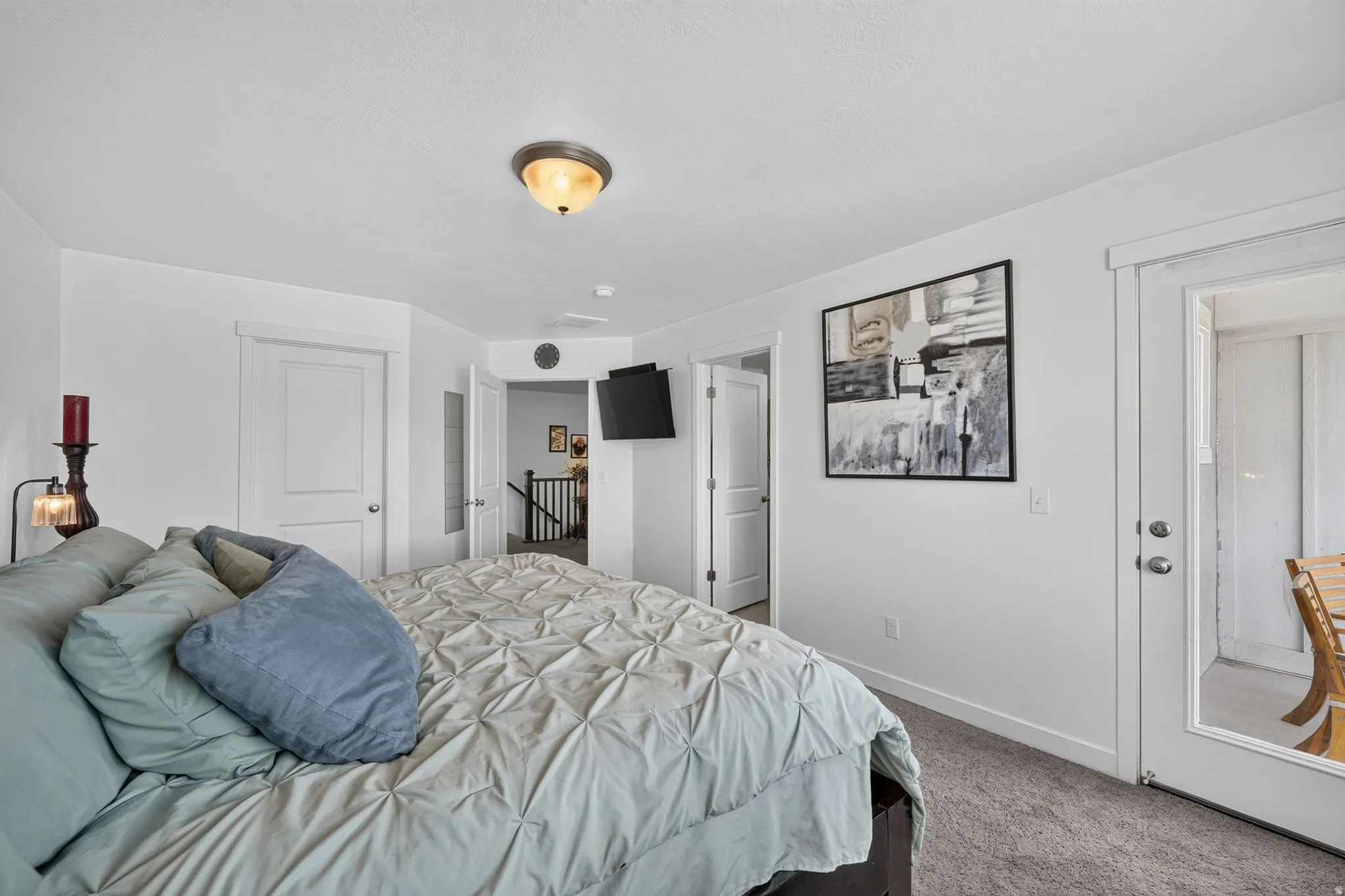 Carpeted bedroom featuring a white door, a glass-paneled exterior door, and a semi-flush mount ceiling light