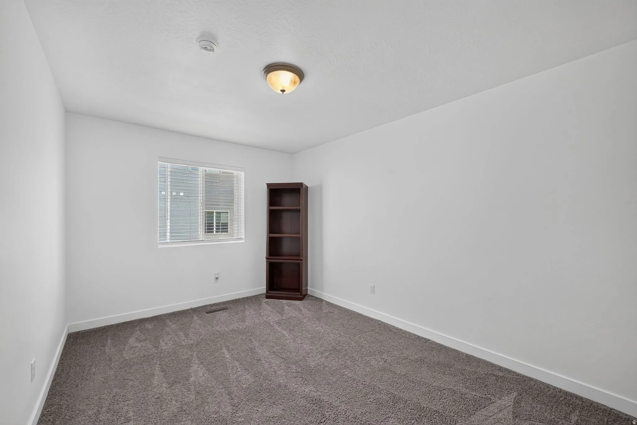 Spacious room featuring neutral carpeting and white walls