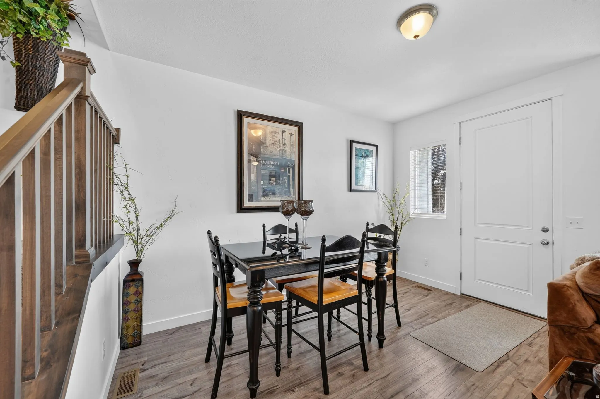 Dining area with wood-finish flooring, white walls, and a contemporary ceiling light fixture