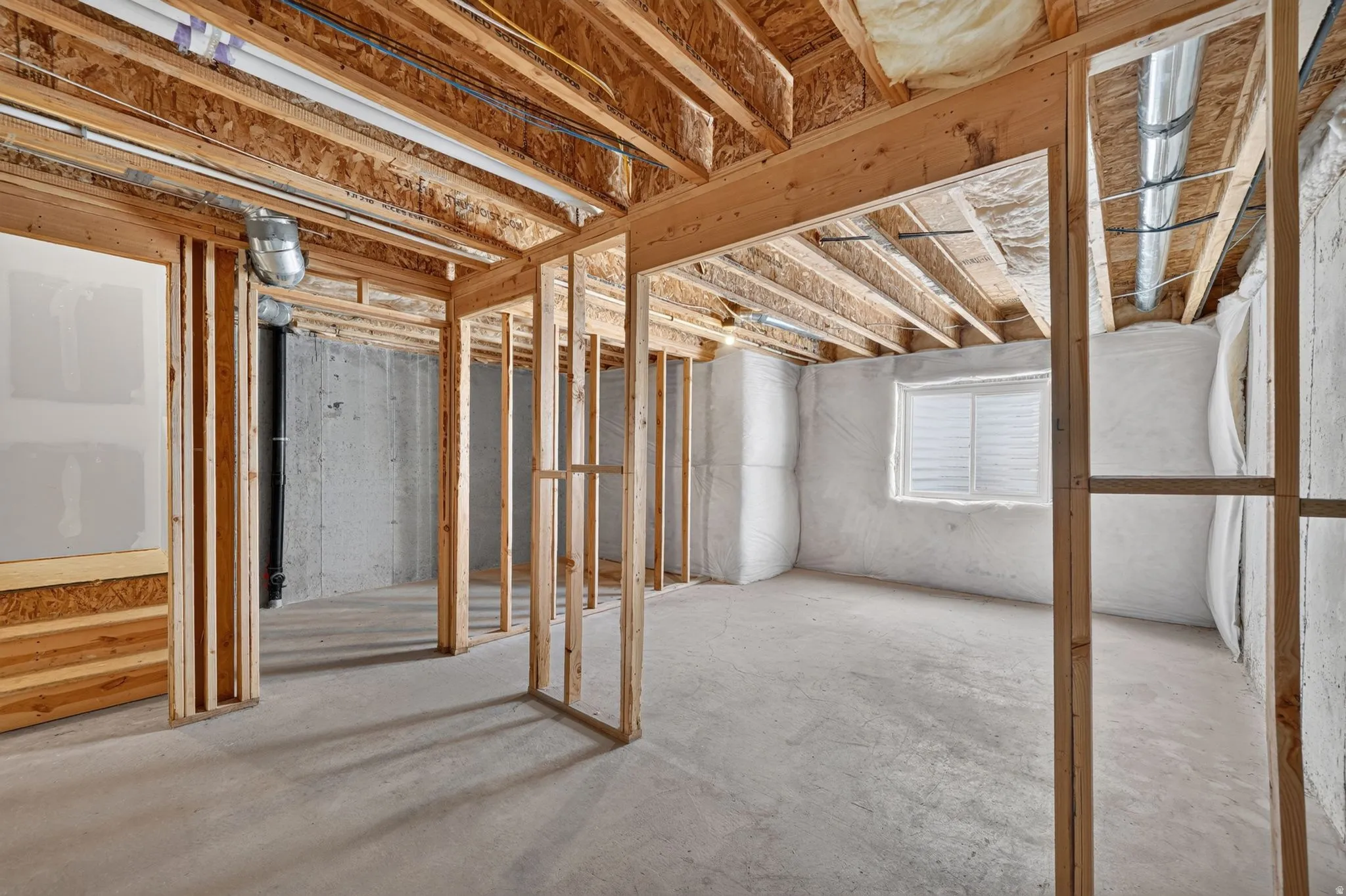 Unfinished basement with concrete flooring and exposed wood framing