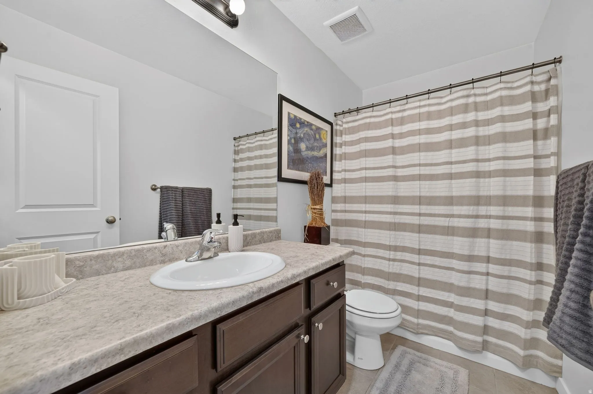Bathroom vanity featuring a laminate countertop with an integrated sink, dark wood-finish cabinetry, and a full-width mirror