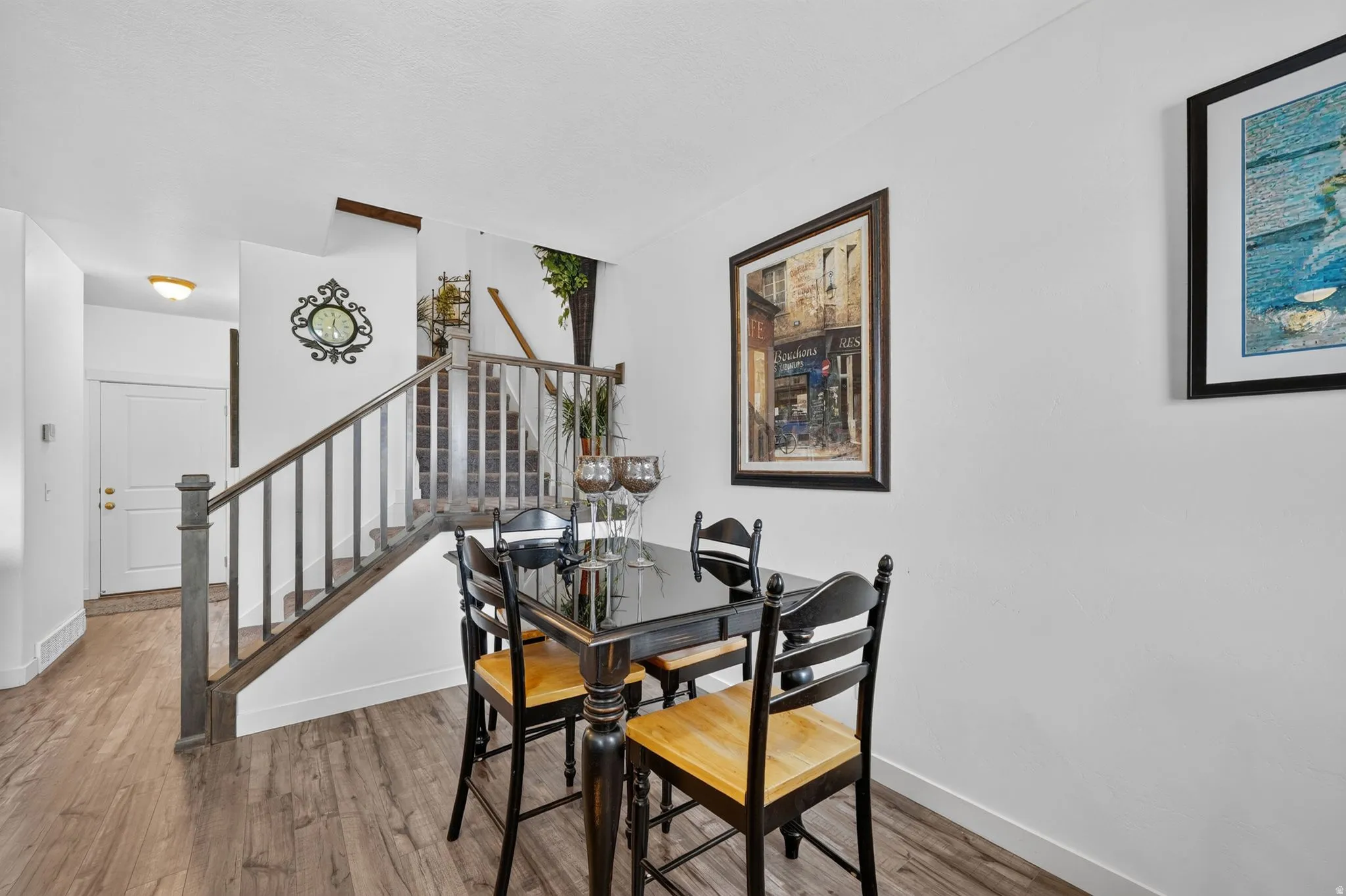 Open-concept dining area featuring wood-finish flooring and a staircase with a dark wood-stained railing
