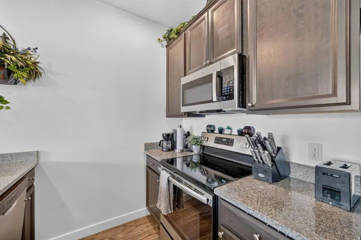 Kitchen area featuring wood-finish flooring, dark wood cabinetry, and speckled countertops