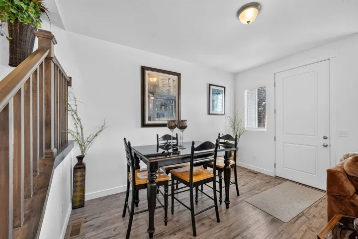 Dining area with wood-finish flooring, white walls, and a contemporary ceiling light fixture