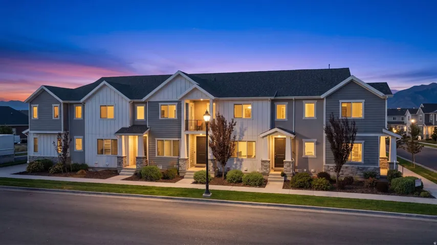 Modern townhome-style residences featuring multi-textured siding, stone veneer accents, individual covered entryways, and private balconies