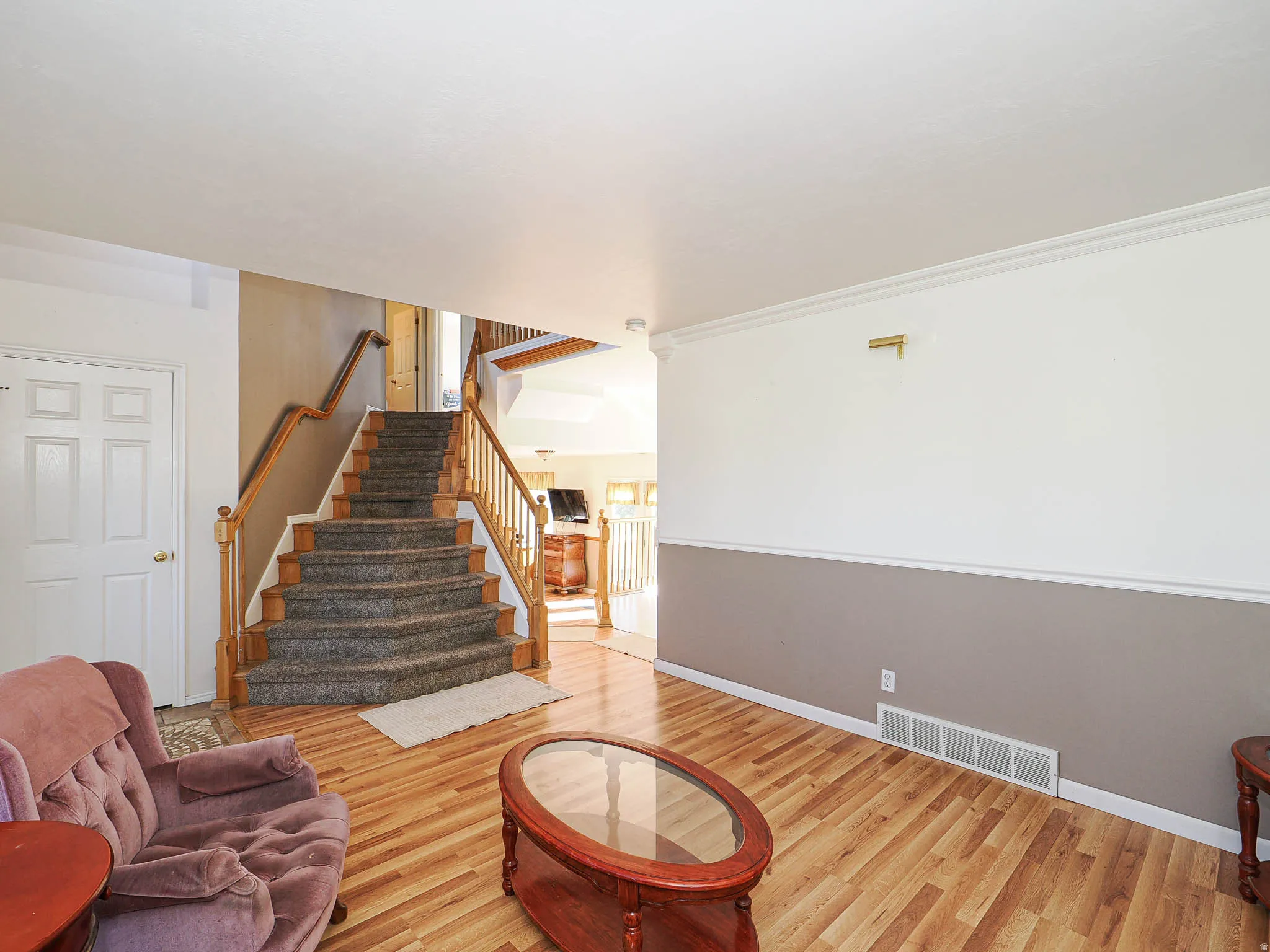 Staircase with wood balusters and carpeted treads, complemented by wood-finish flooring