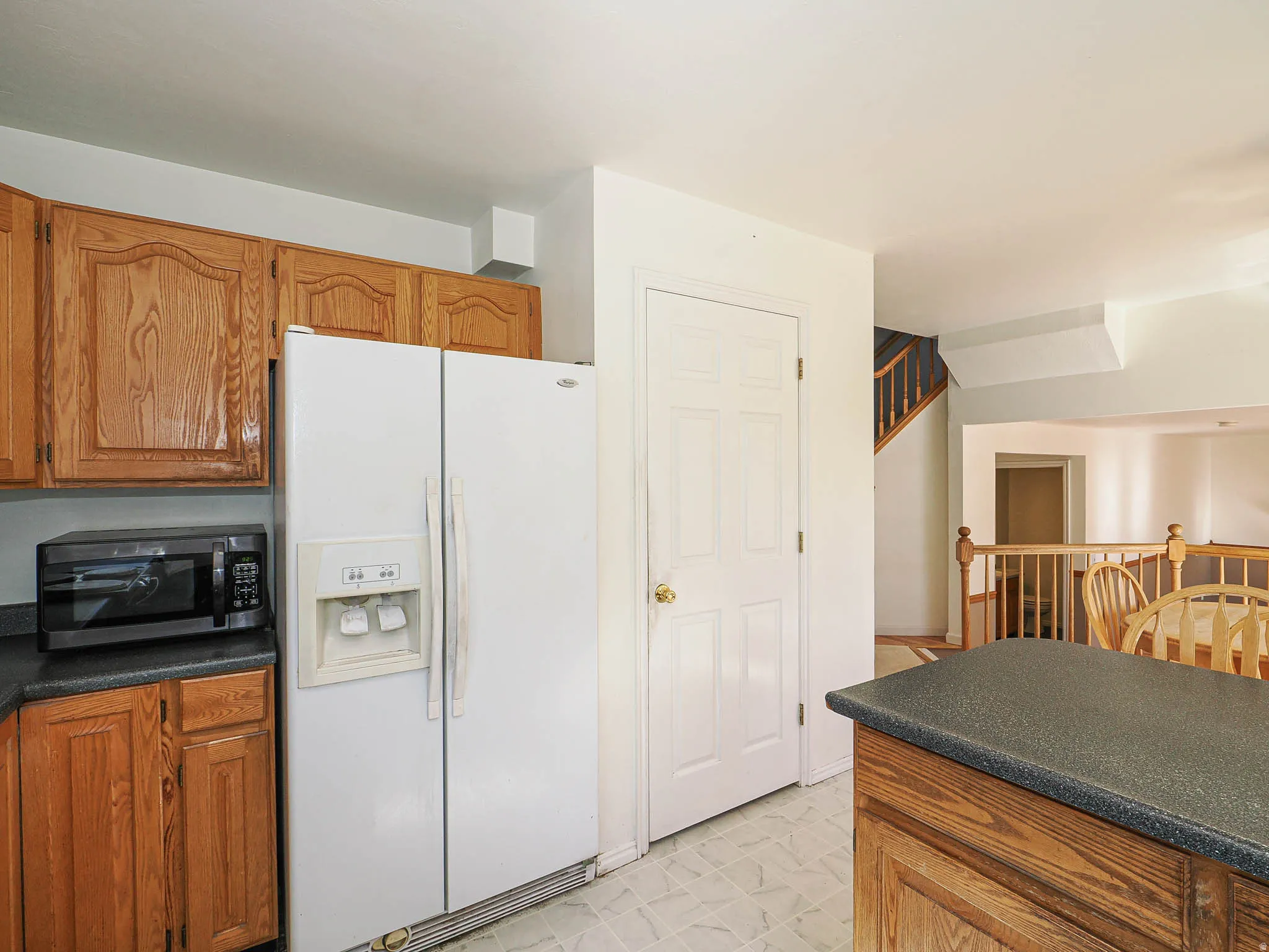 Kitchen with wood cabinetry, dark countertops, and tile flooring