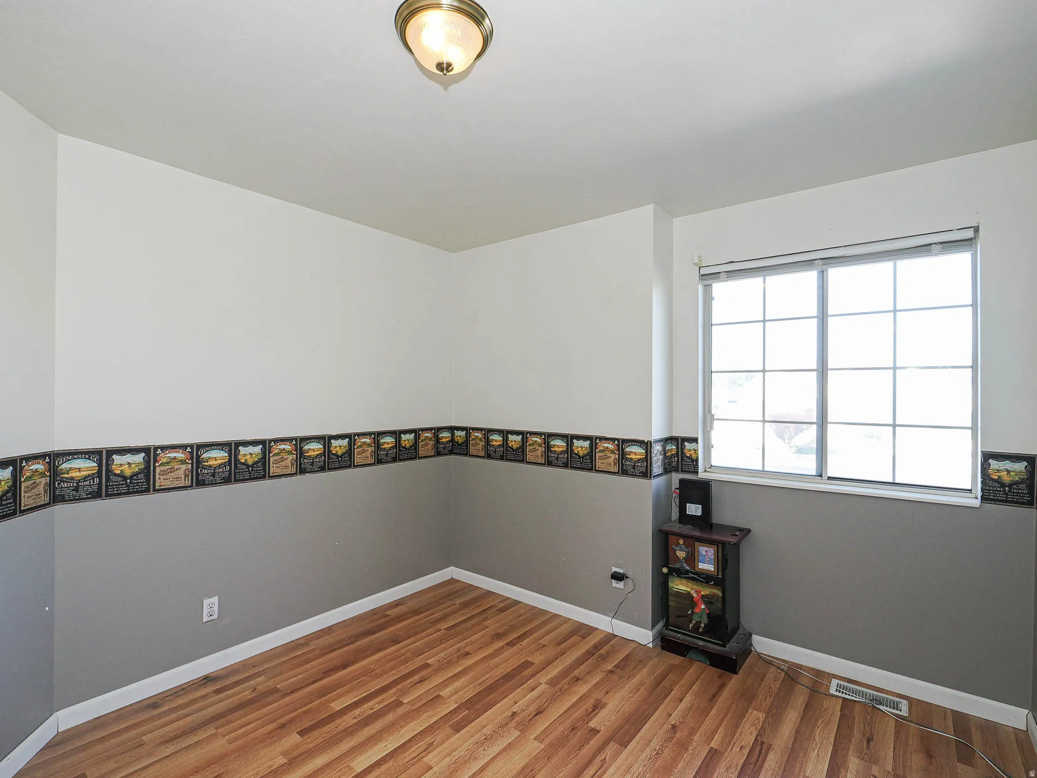 Room featuring wood-finish flooring, a double-pane window, and a flush mount ceiling light fixture