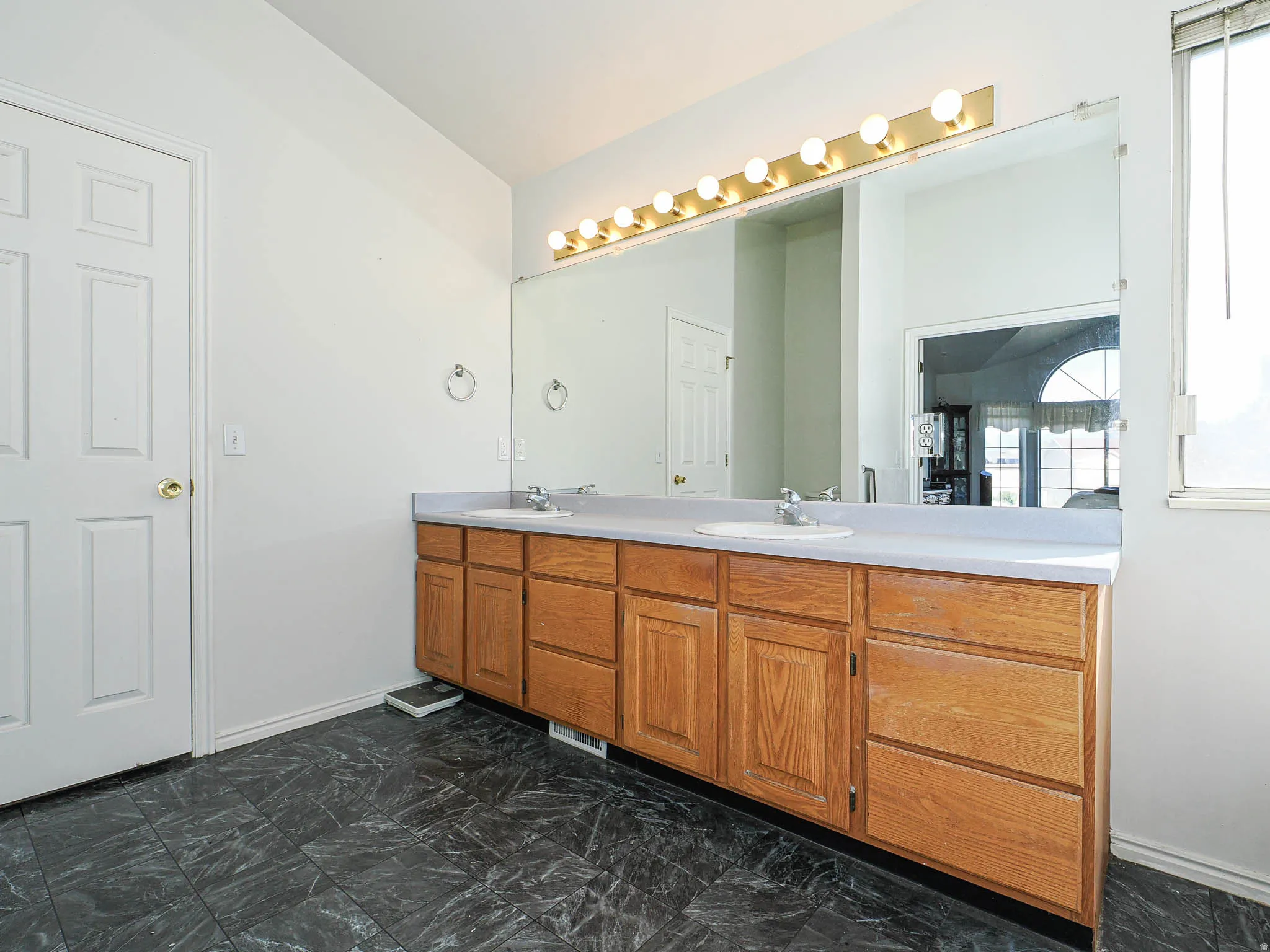 Double vanity with light wood cabinetry, white countertops, and dual integrated sinks