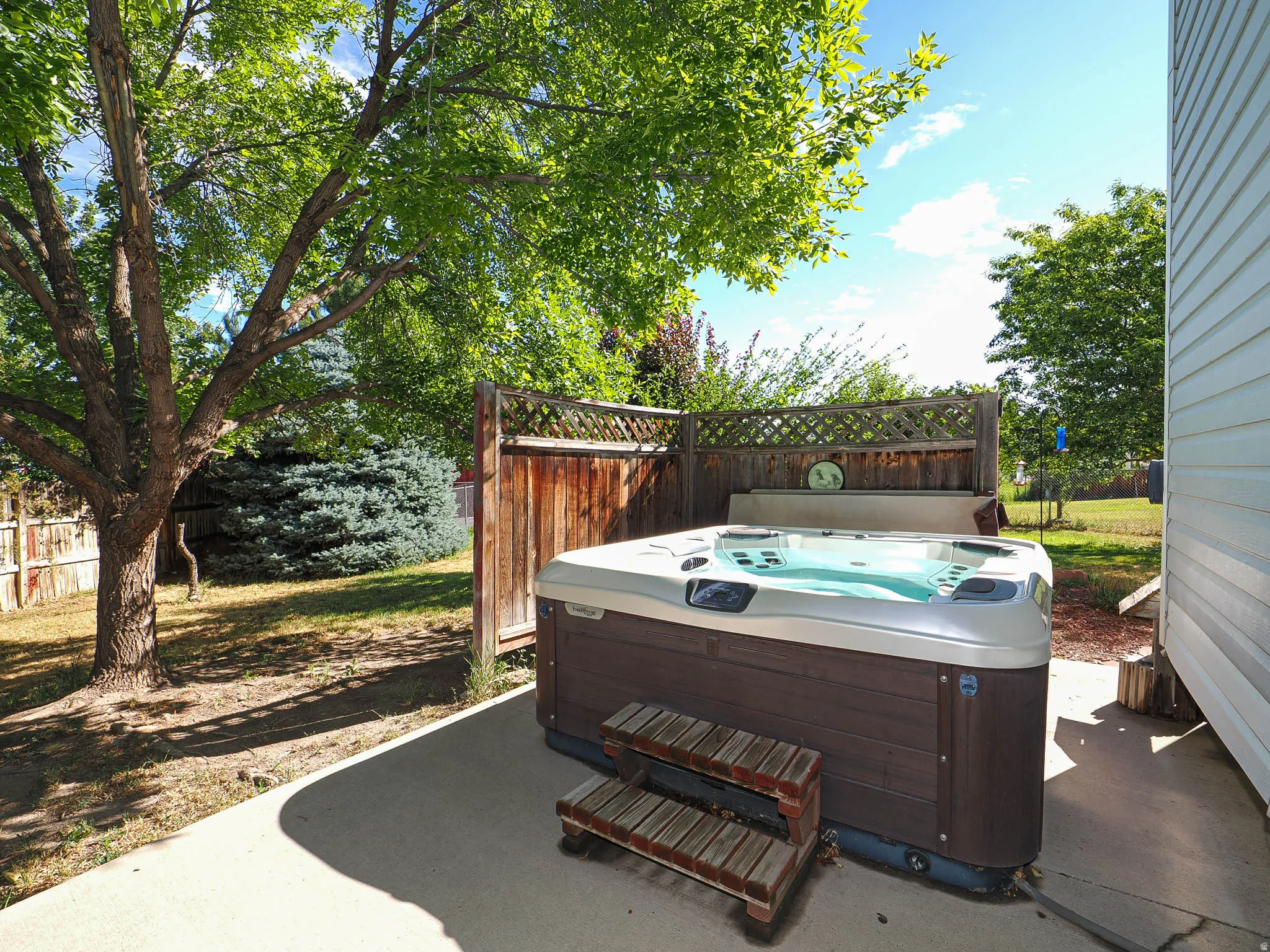 Outdoor spa with wood-finish siding situated on a concrete patio