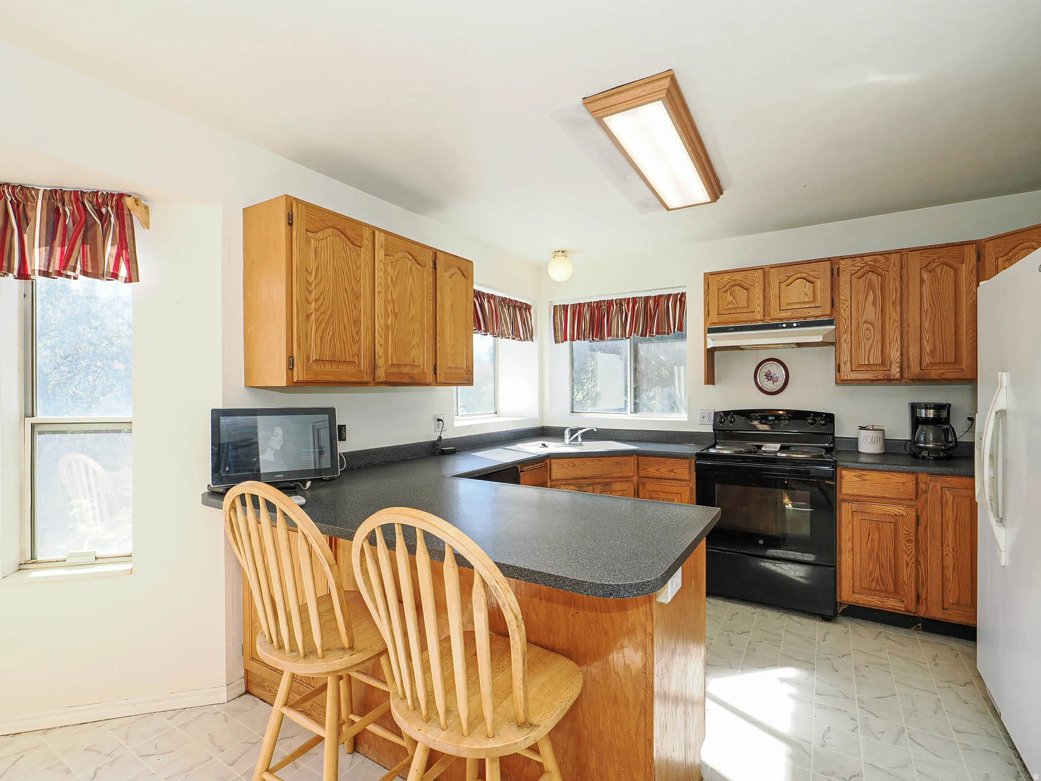 Kitchen featuring light wood cabinetry, dark countertops, and a built-in breakfast bar