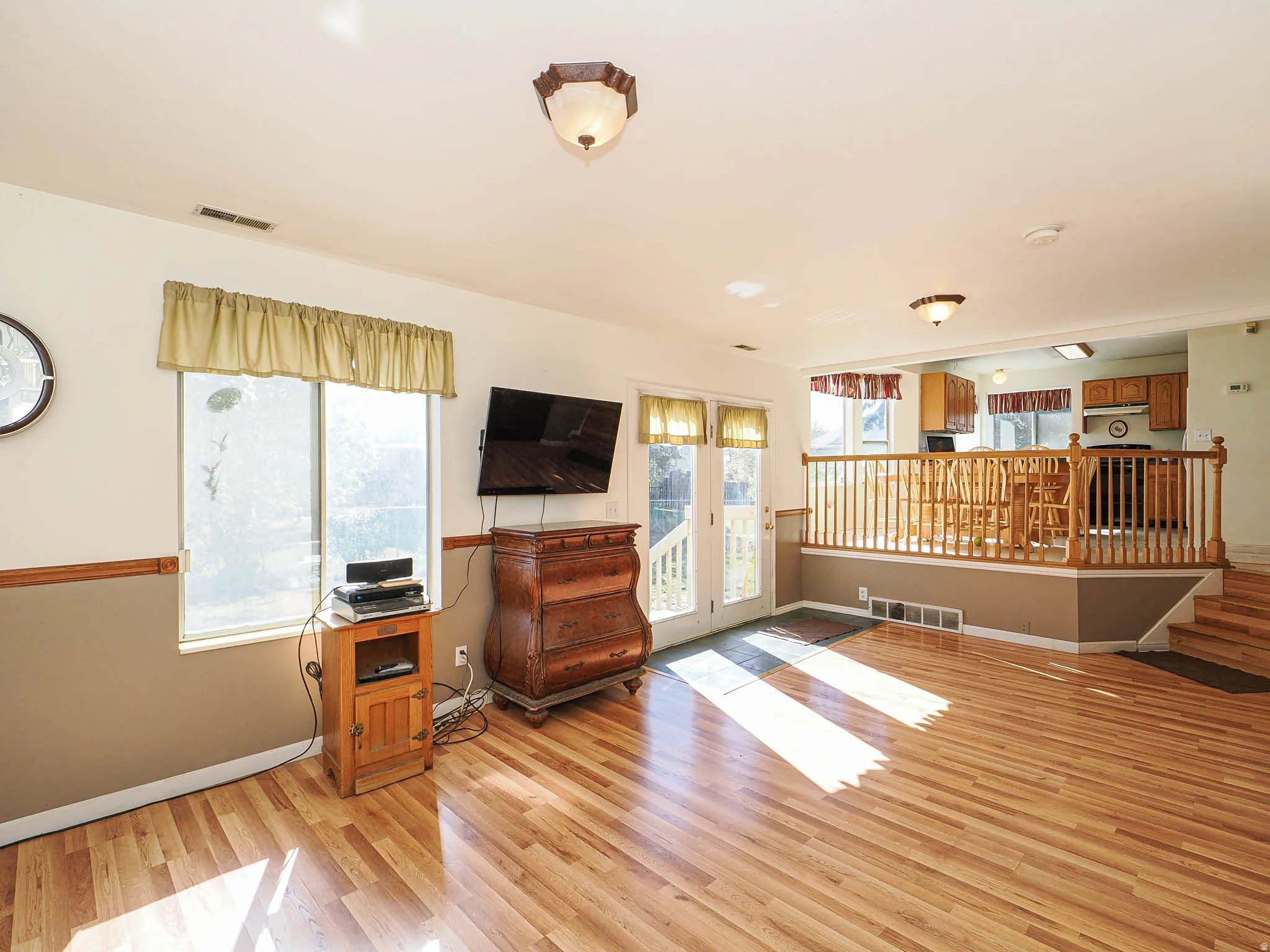Bright living space featuring wood-finish flooring and white walls with a chair rail