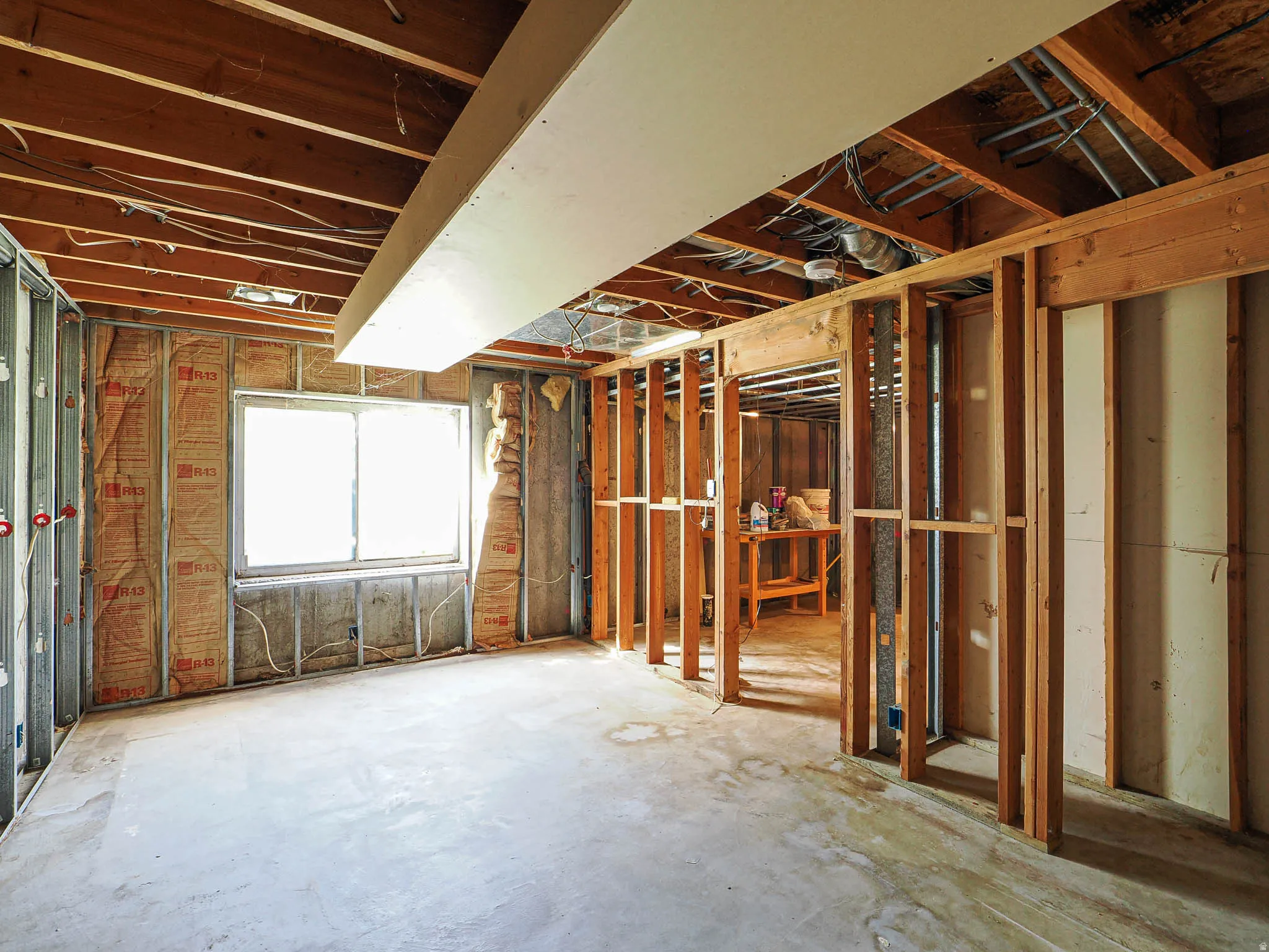 Unfinished lower level featuring exposed wood ceiling joists and concrete flooring