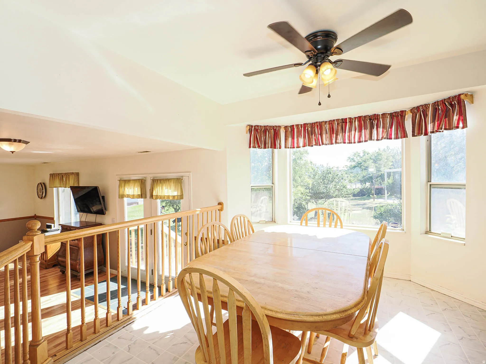 Dining area featuring a bay window, ceiling fan with light fixture, and tile flooring