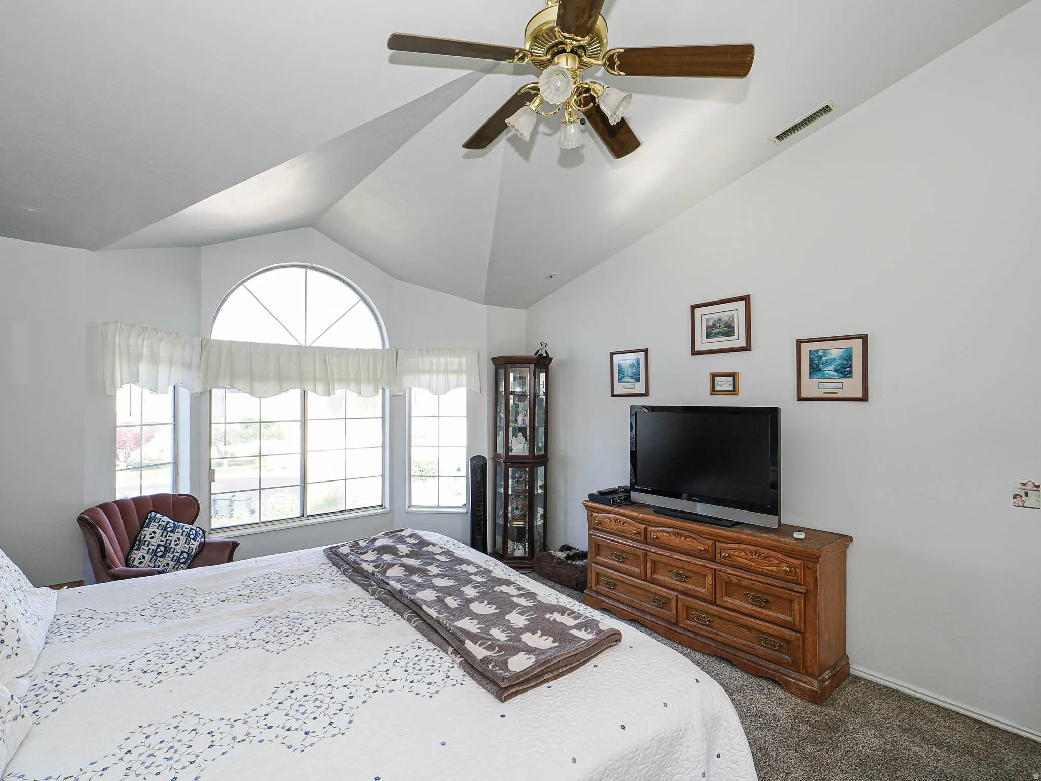 Vaulted ceiling with a ceiling fan, a large bay window, and an arched window feature