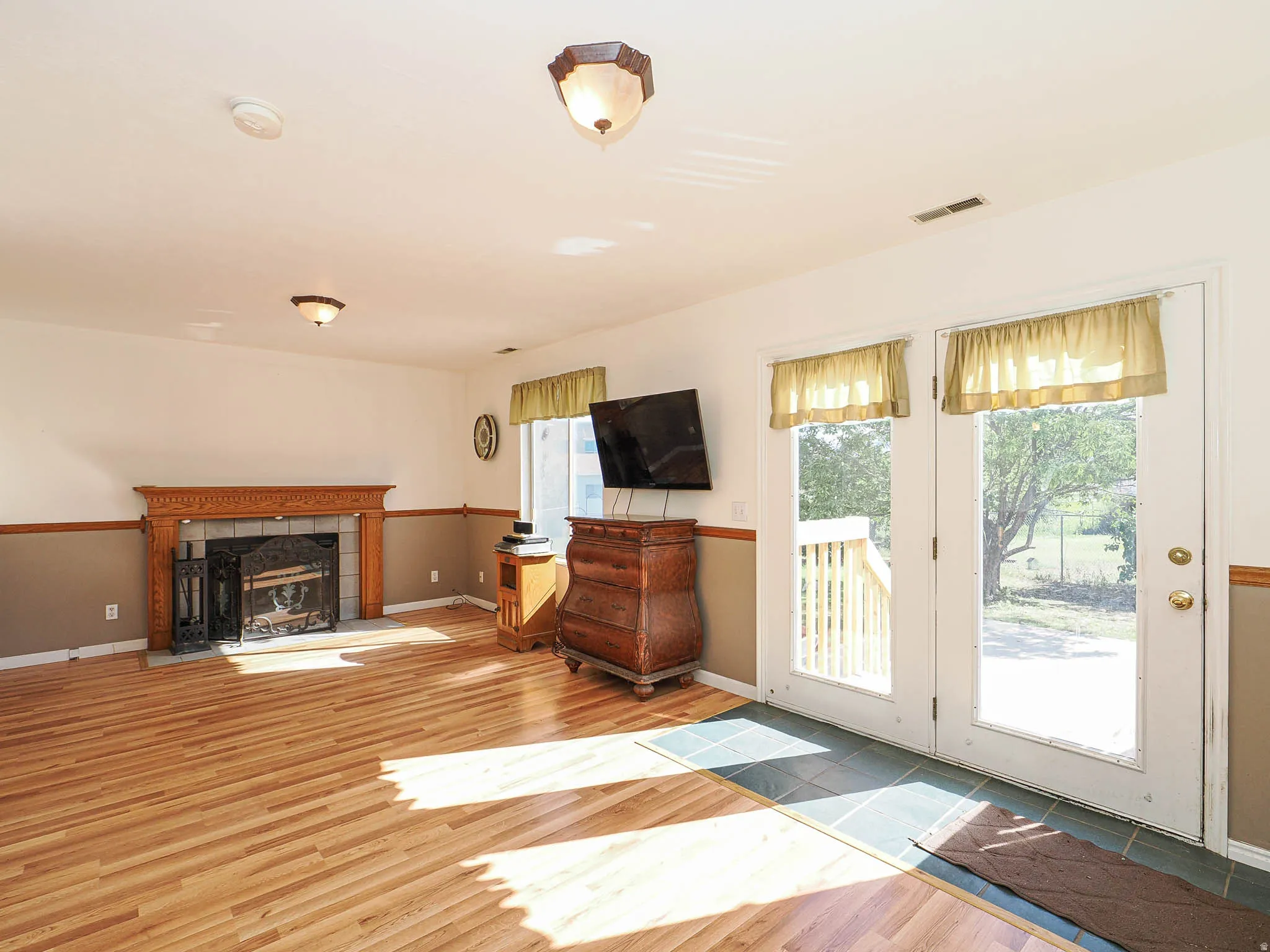 Living area featuring light wood-finish flooring and a decorative fireplace with an ornate wood mantel and dark tile surround