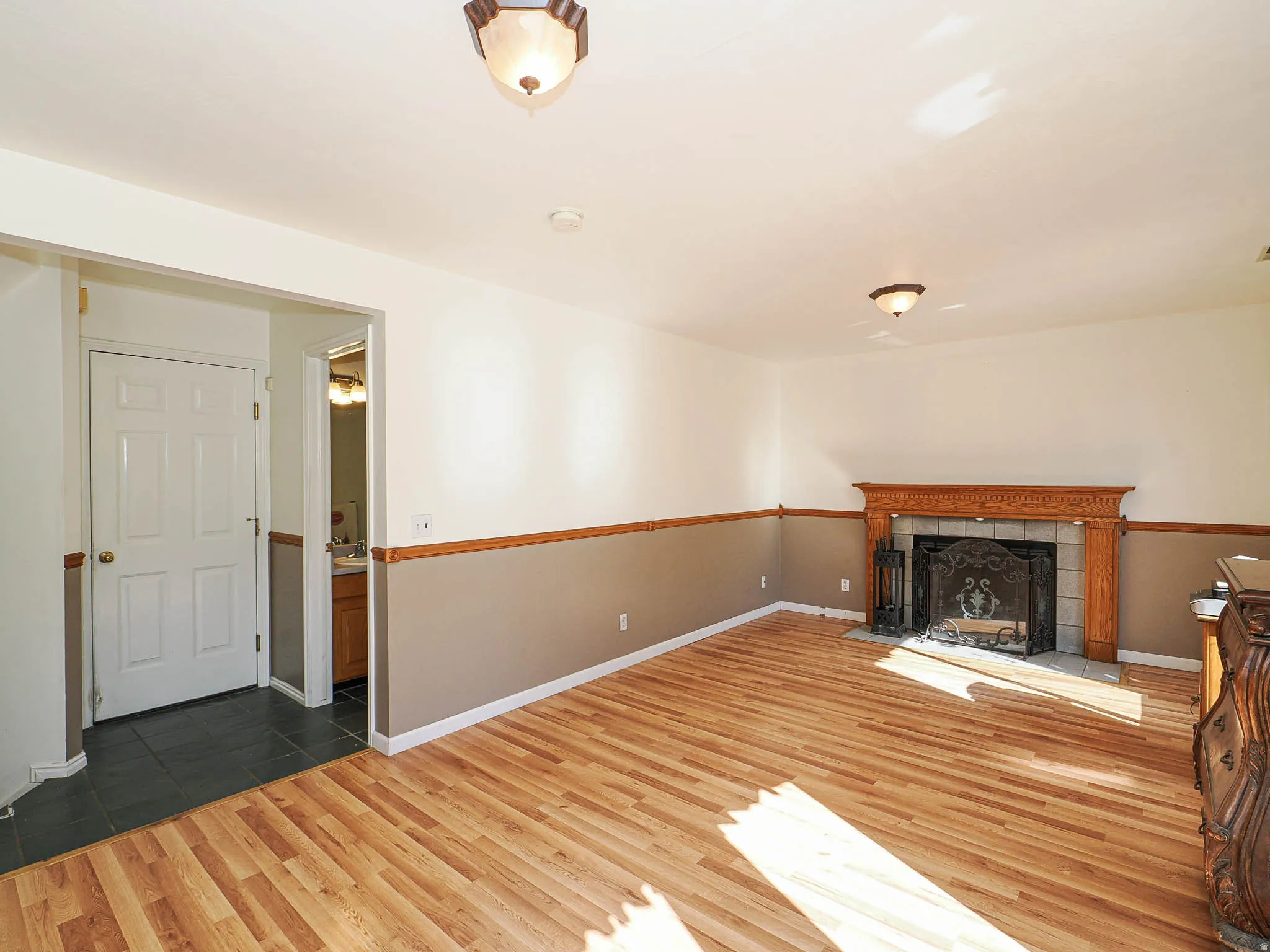 Expansive living area featuring wood-finish flooring and a decorative fireplace with an ornate wood mantel and tile surround