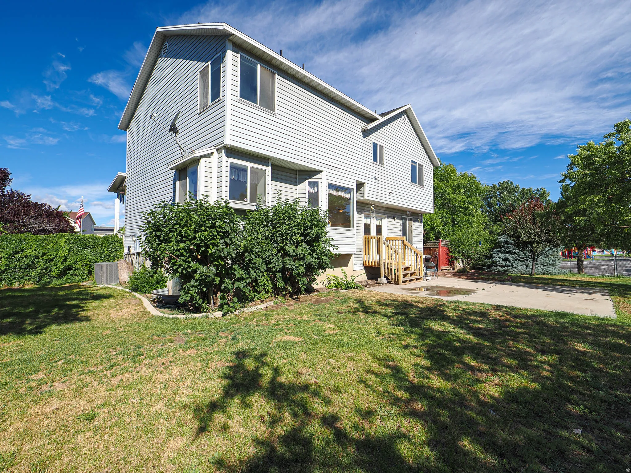 Two-story exterior featuring light gray siding, a gabled roofline, and multiple bay windows