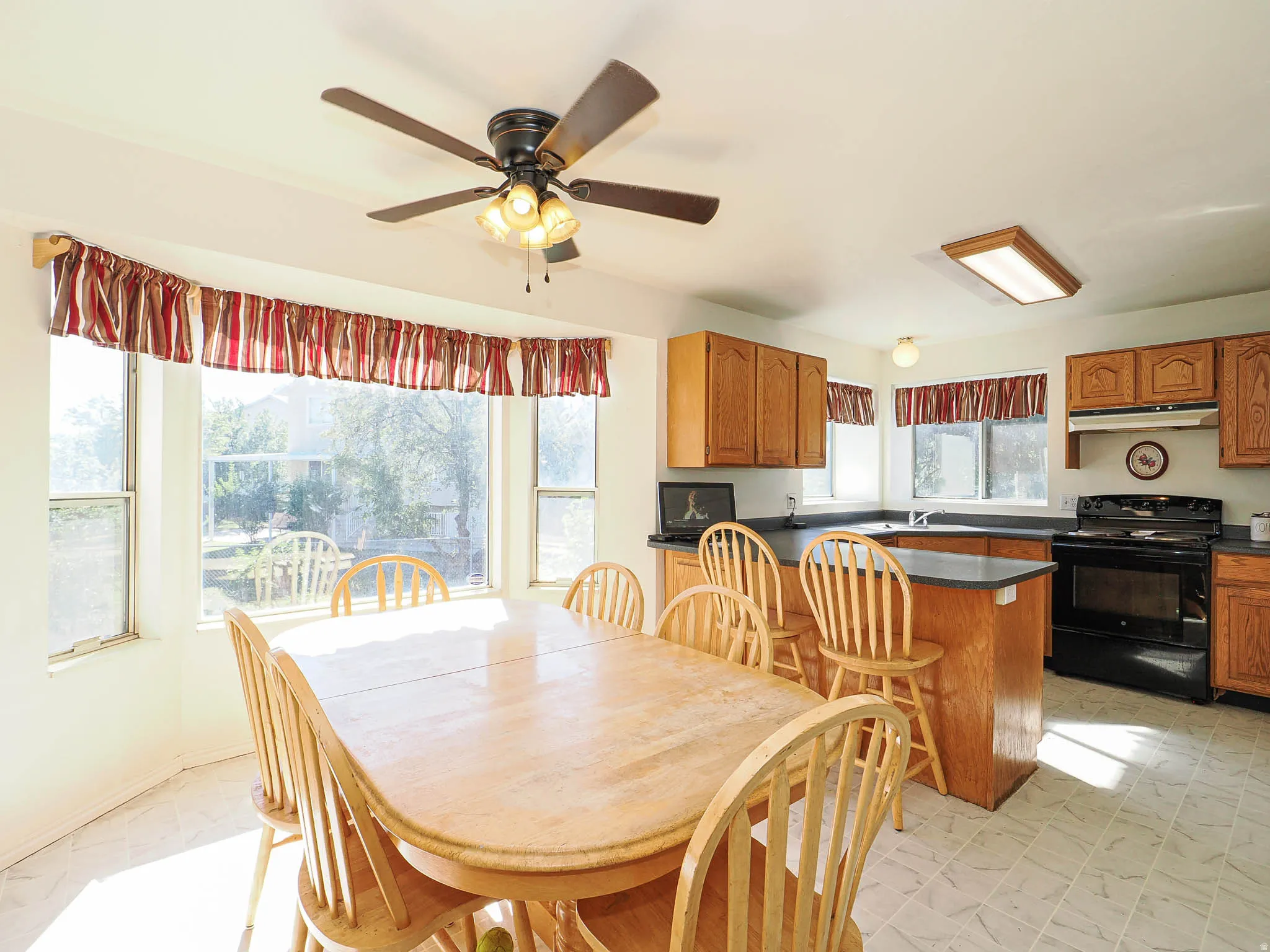 Kitchen with wood-finish cabinetry, dark countertops, and a full suite of black appliances