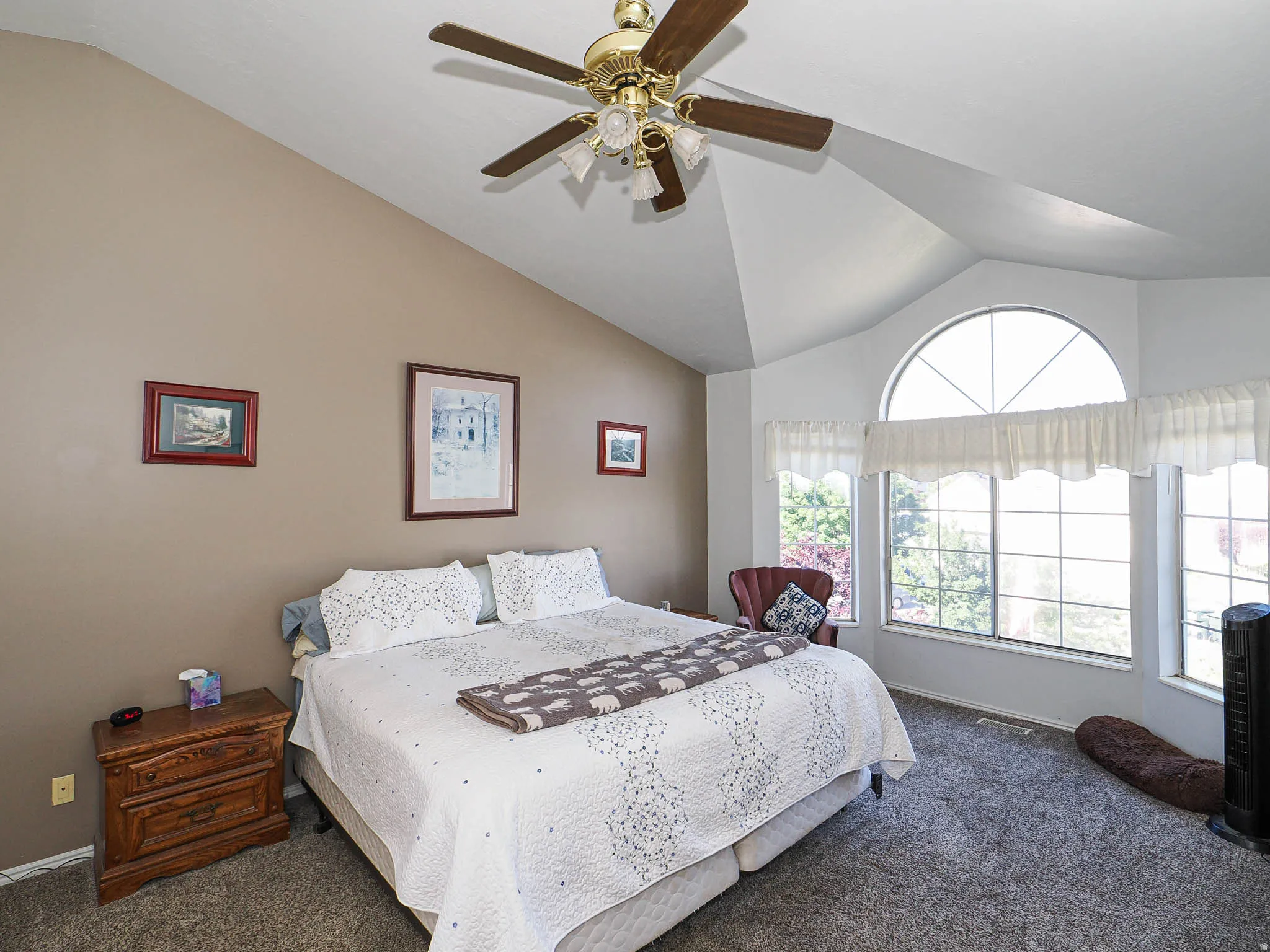 Vaulted ceilings accent a spacious room with carpet flooring