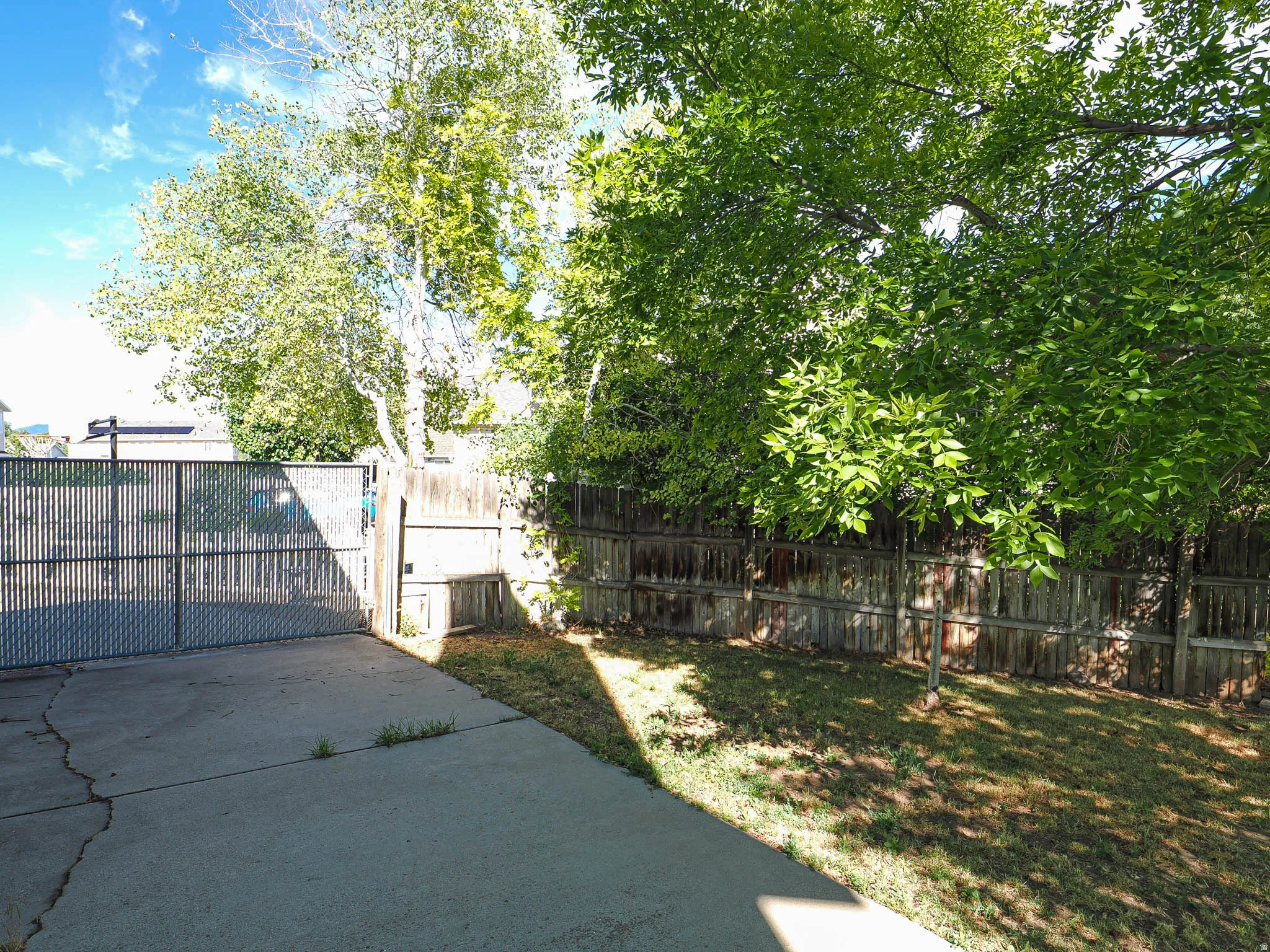 Paved concrete patio and drive area with a chain-link gate