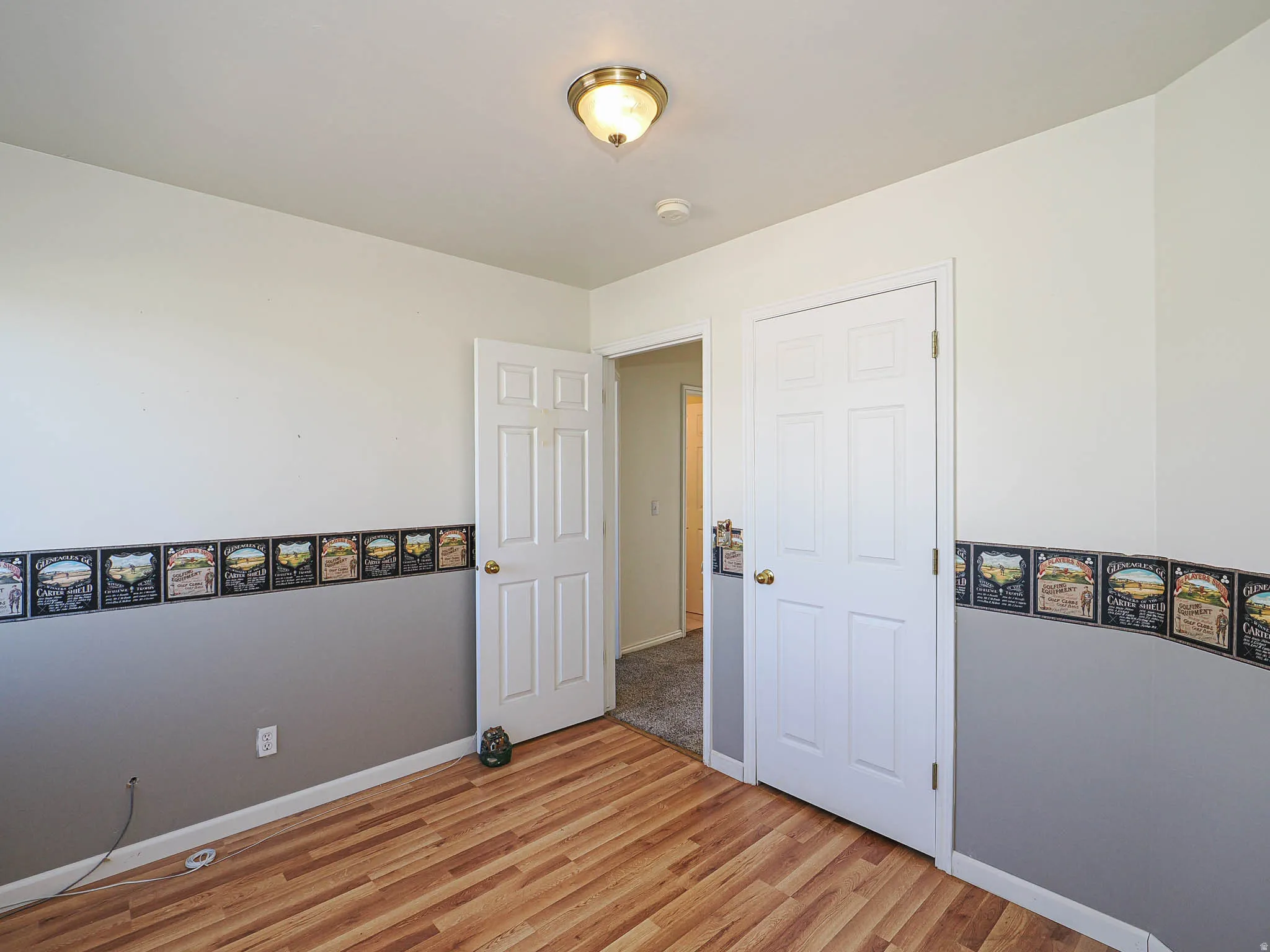 Wood-finish flooring throughout, white baseboards, and a neutral wall color with a decorative border