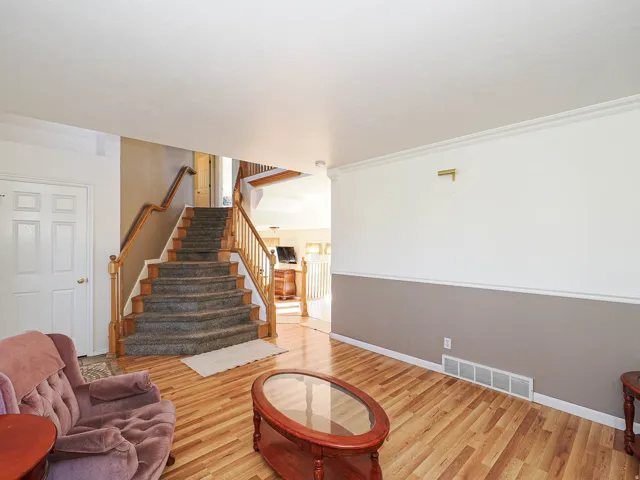 Staircase with wood balusters and carpeted treads, complemented by wood-finish flooring